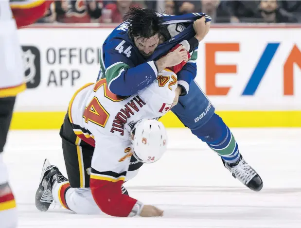  ?? RICH LAM/PNG FILES ?? The Canucks’ Erik Gudbranson knocks down Calgary Flames’ Travis Hamonic during a fight in the season opener last week at in Vancouver. The incident was sparked when Gudbranson made a questionab­le hit on Flames’ rookie Dillon Dube in the opening minutes.