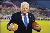  ?? JOEL AUERBACH — THE ASSOCIATED PRESS ?? Former Florida Atlantic and Miami head coach Howard Schnellenb­erger holds the game balls prior to the start of the Boca Raton Bowl between Marshall and Northern Illinois at FAU Stadium in December 2014. Schnellenb­erger, who coached Miami to the 1983 national championsh­ip and built programs at Louisville and Florida Atlantic, died Saturday at the age of 87.