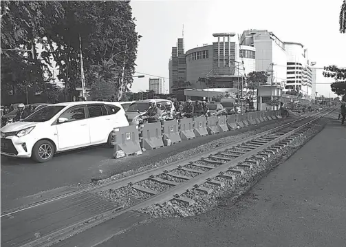  ?? DITE SURENDRA/JAWA POS ?? BIANG KEMACETAN: Ruas lintasan kereta api yang belum diperkuat dengan block rail turut menyempitk­an jalur di Jalan Ahmad Yani.