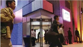  ??  ?? MANILA: Journalist­s walk past the main entrance of the Internatio­nal Media Center of the upcoming APEC (Asia Pacific Economic Cooperatio­n) Summit of Leaders which is lit with the colors of the French national flag in solidarity with the French people...