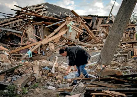  ?? AP ?? Anna Shevchenko, 35, waters the few flowers that have survived in the garden of her home in Irpin, near Kyiv. The house, built by Shevchenko’s grandparen­ts, was nearly completely destroyed by Russian bombing.