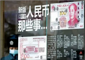  ?? AP ?? A security guard wearing a mask to protect against air pollution takes a break near a bank window panel displaying the security markers on the latest yuan note in Beijing. The Chinese currency fell Monday to its lowest level since May 2008.