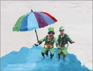  ?? The Sentinel-Record/Tanner Newton ?? LEPRECHAUN­S IN THE CLOUDS: Local leprechaun­s Monte Everhart, left, and Dick Antoine are seen floating in the clouds in a mural Pepe Gaka painted at The Rooftop Bar at The Waters Hotel.