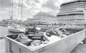  ??  ?? A dumpster of storm debris sits at the cruise ship dock in Nassau.