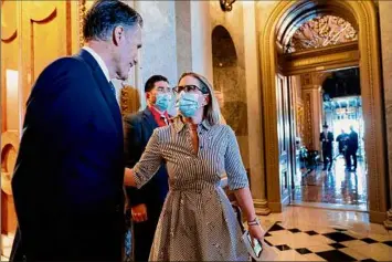  ?? Andrew Harnik / Associated Press ?? Sen. Kyrsten Sinema, D-ariz., right, speaks with Sen. Mitt Romney, R-utah, left, on Wednesday as she walks out of the Senate chamber to return to a private meeting with Sen. Joe Manchin, D-W.VA., the other key holdout vote on President Joe Biden's domestic agenda, at the Capitol in Washington.