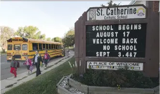  ?? JOHN LUCAS/ EDMONTON JOURNAL ?? Principal Dwain Tymchyshyn walks students in on the first day of school at St. Catherine School in Edmonton on Monday. A transit plan would save $ 2.5M a year and mean shorter bus rides.