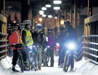  ?? CLIFFORD SKARSTEDT/EXAMINER FILES ?? Avid cyclists make their way across the footbridge between the Holiday Inn and East City during last year's Holiday Lights Glow Ride presented by B!KE: The Peterborou­gh Community Cycling Hub. The event returns this Wednesday.