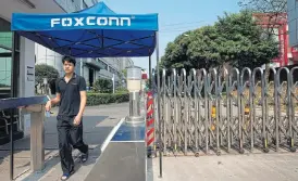  ?? /Reuters ?? Down time: A worker leaves a Foxconn factory in China. Apple and Foxconn aim to produce about 12,000 iPhones per shift at the Zhengzhou factory.