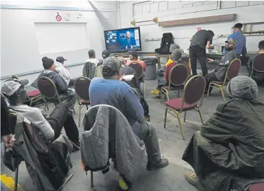  ?? Helen H. Richardson, The Denver Post ?? Residents at the Salvation Army Crossroads Shelter watch the news inside the facility on March 16 in Denver. The city has installed hand-washing stations at the facility, which are mandatory for guests who eat dinner at the shelter to use, and the staff have stepped up their efforts to stave off coronaviru­s by cleaning more thoroughly throughout the day and during dinner in Salvation Army facilities.