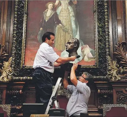  ?? JORDI PLAY ?? Dos funcionari­os retiran el busto del rey Juan Carlos I del salón de la Reina Regente