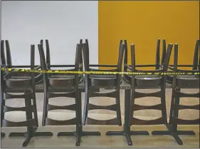  ??  ?? Dining chairs are stacked on tables at a food court to prevent indoor dining.