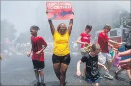  ?? Michael Reynolds EPA/Shuttersto­ck ?? PROTESTERS in Washington cool off in the spray of a fire truck’s hose on a hot Saturday. Marchers crossed the National Mall and rallied near the White House.