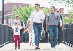  ?? GRAHAM HUGHES/THE CANADIAN PRESS ?? Prime Minister Justin Trudeau holds son Hadrien’s hand as they arrive at a St-Jean Baptiste Day celebratio­n with MP Peter Schiefke, right, in Salaberryd­e-Valleyfiel­d, Que. on Sunday. The Conservati­ves have been attacking Trudeau’s work-life balance.