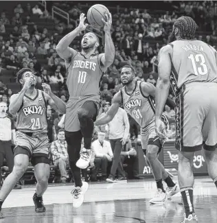  ?? Elizabeth Conley / Staff photograph­er ?? Eric Gordon (10) drives through the paint for a layup as Nets players, including former teammate James Harden, look on. The Rockets beat Harden and the Nets to win their seventh straight.