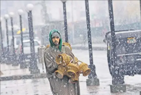  ?? HT PHOTOS: WASEEM ANDRABI ?? ■ A street vendor sells kangris in Srinagar. The traditiona­l clay bowl encased in a wicker basket still keeps Kashmiris warm especially during the state’s extended power cuts.