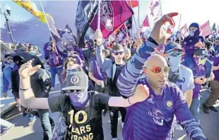  ?? JOE BURBANK/AP ?? Orlando City fans march to Exploria Stadium ahead of the Lions’ home opener on Feb. 29, shortly before the coronaviru­s pandemic forced the league to suspend play.