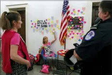  ?? JACQUELYN MARTIN - THE ASSOCIATED PRESS ?? Code Pink co-founder Medea Benjamin, center, gestures as she talks with Capitol Police outside the office of Rep. Ilhan Omar, D-Minn., Friday, where heart shaped Post-its line the wall as part of a day-long solidarity vigil organized by the anti-war group, on Capitol Hill in Washington. Capitol Police asked them to remove the chairs and table, and the women complied.