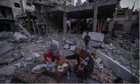  ?? — AFP photo ?? The Palestinia­n Al-Naji family prepare to break their fast during the first day of the Muslim holy fasting month of Ramadan sitting amidst the ruins of their family house in Deir el-Balah, central Gaza Strip.