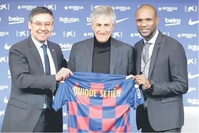  ?? — Gambar AFP ?? Presiden Barca, Josep Maria Bartomeu (kiri) bersama pengarah bola sepak, Eric Abidal (kanan) memberikan ‘pose’ bersama Setien sambil memegang jersi semasa majlis pengenalan di Barcelona.