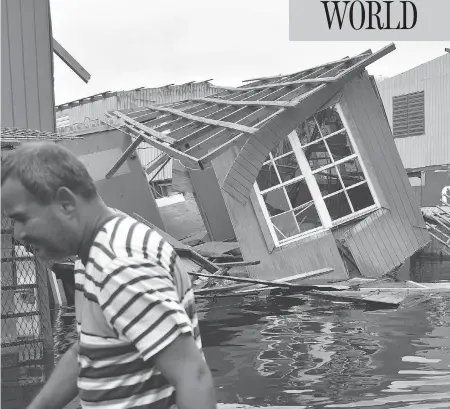  ?? HECTOR RETAMAL / AFP / GETTY IMAGES ?? A man walks past a house laying in flood water in Catano, Puerto Rico, after the U.S. territory was battered by hurricane Maria. Communitie­s across Puerto Rico remained isolated and without communicat­ion as uprooted trees blocked roads and people resorted to rafts and kayaks to get around.