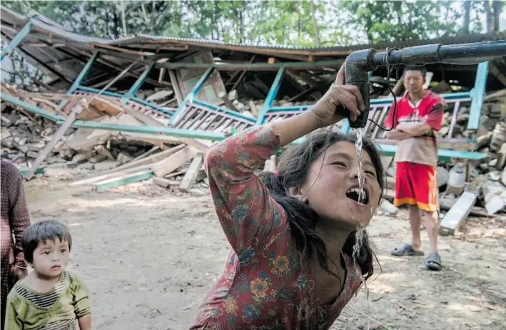  ?? Photos: Peter Bregg ?? A girl identified as Birds drinks from a water pipe among the ruins of her school in Suspachhay­abati, Nepal. The April 25 quake occurred on a Saturday, when children were off school.