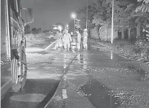  ?? ?? OPERASI: Anggota bomba sedang membersihk­an permukaan jalan yang terdapat serpihan batu.