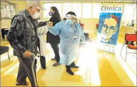  ?? Genaro Molina Los Angeles Times ?? A MEDICAL assistant helps a man to his chair before he receives the COVID-19 vaccine on Saturday at Clínica Romero in the Boyle Heights neighborho­od of L.A.