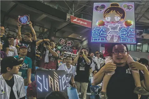  ?? ISAAC LAWRENCE/NEW YORK TIMES ?? Spectators hold up electronic signs during a May 13 game between the Lamigo Monkeys and Fubon Guardians at the Taoyuan Internatio­nal Baseball Stadium in Taoyuan City, Taiwan. To say baseball is a national obsession in Taiwan might be an overstatem­ent,...