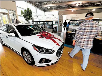  ?? AP/DAVID ZALUBOWSKI ?? A car shopper walks past a 2018 Sonata sitting amid an assortment of models on the showroom floor of a Hyundai dealership in the south Denver suburb of Littleton, Colo., in early October.