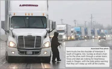  ?? Associated Press photo ?? Semi-trucks line the shoulder of Interstate 5 south of Eugene, Ore. Sunday as drivers chain up for the drive north through a winter storm. Snow and sleet are making for treacherou­s roads in Oregon, with the state police warning that they can't keep up...