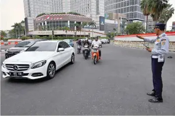  ??  ?? Transport officers guide traffic after traffic lights stopped working due to an electricit­y outage in Jakarta. — AFP