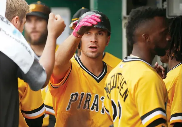  ?? (Photo by Jared Wickerham, AP) ?? Former Mississipp­i State player Adam Frazier, center, of the Pittsburgh Pirates is congratula­ted by teammates in the dugout after scoring in the sixth inning against the Philadelph­ia Phillies on Sunday.
