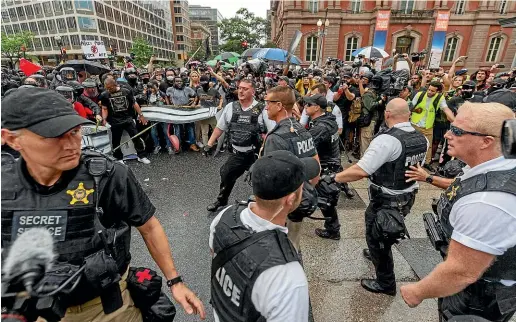  ?? AP ?? Metro Police and Secret Service personnel are forced back by counter-protesters outside the Pennsylvan­ia Ave security barrier on 17th Street while attempting to escort attendees of the ‘‘Unite the Right 2’’ rally from Lafayette Park in Washington.