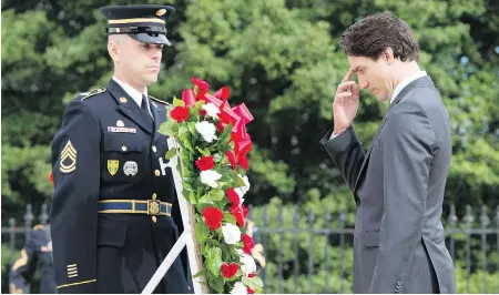  ?? PAUL CHIASSON / THE CANADIAN PRESS ?? Prime Minister Justin Trudeau makes the sign of the cross after laying a wreath Friday at the Tomb of the Unknown Soldier in Arlington Cemetery.
