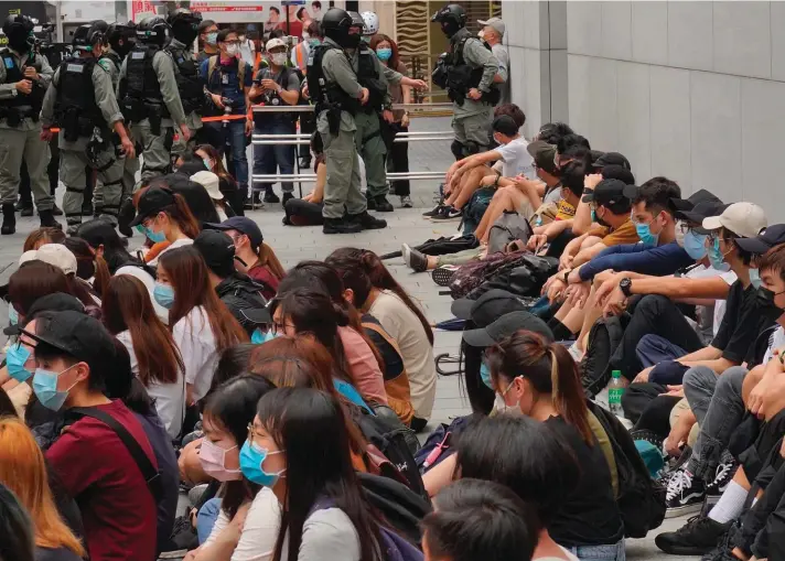  ??  ?? Riot police guard arrested anti-government protesters in the Causeway Bay district of Hong Kong, yesterday. Hong Kong police massed outside the legislatur­e complex Wednesday, ahead of debate on a bill that would criminaliz­e abuse of the Chinese national anthem in the semi-autonomous city. Photo: AP