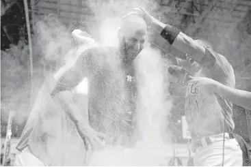  ??  ?? Mike Fiers, center, earns a shower of talcum powder and a water courtesy of his teammates following his nohitter against the Dodgers.