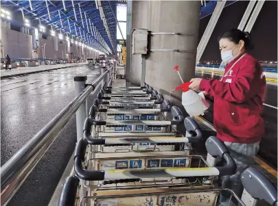  ??  ?? An airport worker disinfects trolleys at Pudong Internatio­nal Airport yesterday. — Ti Gong
