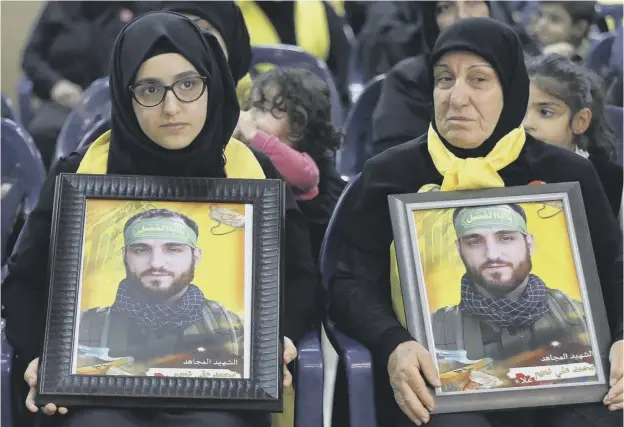  ??  ?? Shiite women carry pictures of relatives who died fighting for Hezbollah as Hezbollah leader Sheik Hassan Nasrallah addresses a rally marking Martyr’s Day in Beirut