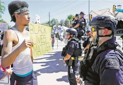  ?? LM Otero / Associated Press ?? A protester faces off with police outside Gateway Church in Dallas, where President Donald Trump said he’ll push in the opposite direction of demonstrat­ors’ calls to defund and dismantle police department­s and instead try to boost resources.