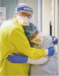  ??  ?? ABOVE: Frost 19 team members Kimberly Miller and Yoselin Marquez share a quick hug Thursday during their shift in the COVID-19 ward.