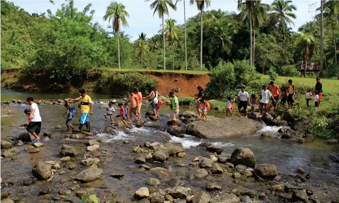  ?? (RICHEL V. UMEL) ?? FIRST DAY OF SCHOOL. Subanen children cross a stream with their parents during the start of the school year Monday, June 4, 2018, in Kapatagan town, Lanao del Norte