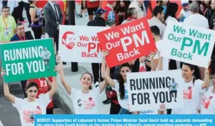  ??  ?? BEIRUT: Supporters of Lebanon’s former Prime Minister Saad Hariri hold up placards demanding his return from Saudi Arabia on the starting line of Beirut’s annual marathon yesterday.