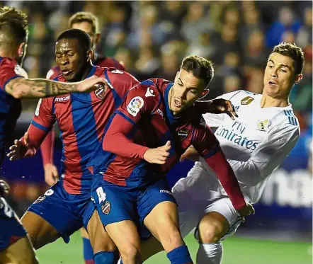  ?? — AFP ?? I can’t see, guys!: Real Madrid’s Cristiano Ronaldo (right) eyeing the ball from behind Levante players in the La Liga match at the Ciutat de Valencia Stadium on Saturday.