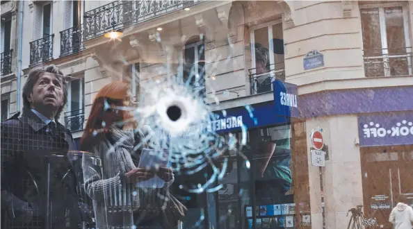  ?? Pictures: AP PHOTO, AFP, WLADIA DRUMMOND ?? CARRY ON: Paris returns to normal yesterday as shoppers pass a cafe where a bullet struck during the police shooting of Khamzat Azimov (below, left) who stabbed and killed one man (below, right) during a knife rampage on the weekend that also injured...