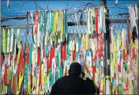  ?? Picture: REUTERS/ KIM HONG-JI ?? LONGING FOR UNIFICATIO­N: A man peeps through a barbed-wire fence with ribbons bearing pro-unificatio­n messages near the demilitari­sed zone in Paju, South Korea