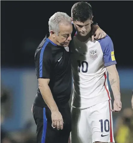  ?? REBECCA BLACKWELL/THE ASSOCIATED PRESS ?? Christian Pulisic is comforted by a member of the team staff after the U.S. men failed to qualify for the World Cup after losing 2-1 in Couva, Trinidad and Tobago, on Tuesday.