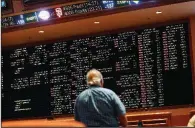  ?? AP/JOHN LOCHER ?? A man checks out the sports betting odds at a casino in Las Vegas on Monday, the day the U.S. Supreme Court indicated its leanings regarding the Constituti­on’s 10th Amendment.