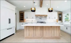  ??  ?? The radiant kitchen boasts white cabinetry, a farmhouse sink and a large island with a breakfast bar.