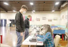  ?? LYNN KUTTER ENTERPRISE-LEADER ?? Prairie Grove High seniors Blake Gardner, left, and Knox Laird prepare to receive their ballots for the Feb. 9 special election in Prairie Grove. Election official Peggy Hatfield is assisting Gardner. City voters approved all nine questions on the election ballot.