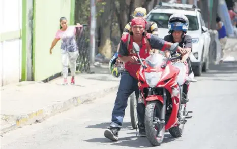  ??  ?? »Los saqueadore­s se van con una motociclet­a que acaban de sacar de una tienda en Managua.